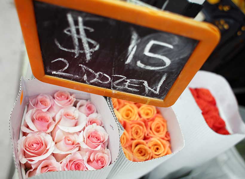 Bouquets of pink, orange, and red roses with a sign above showing a price.